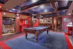 a pool table in the middle of a living room with red walls and blue carpet