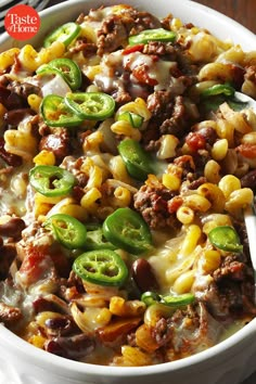 a white bowl filled with pasta and meat covered in cheese, green peppers and sauce