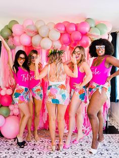 a group of women standing next to each other in front of pink and green balloons