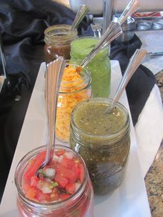 three jars filled with different types of food on top of a white countertop next to each other