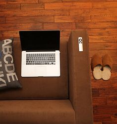 a laptop computer sitting on top of a couch next to a pair of slippers