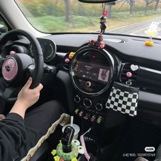 a person driving a car with a steering wheel and various decorations on the dash board