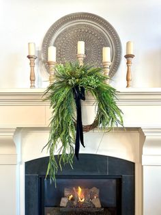 a fireplace with a potted plant hanging over the mantle and candles on either side