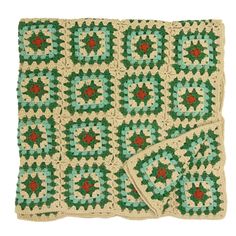 a crocheted blanket with green and red flowers on it