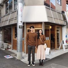 a man and woman standing in front of a building