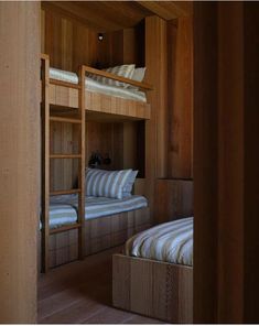 two bunk beds in a room with wood paneling and white striped pillows on them