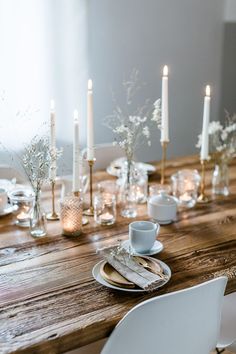 a wooden table topped with white plates and candles