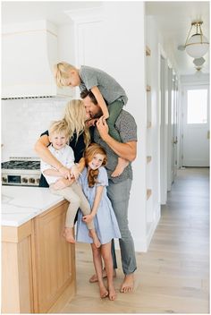 a woman and two children standing in front of a kitchen counter with an island top