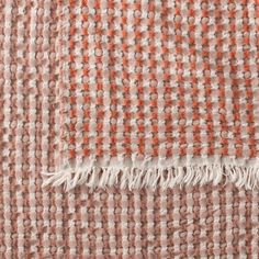 an orange and white checkered blanket with fringes on the edges, close up