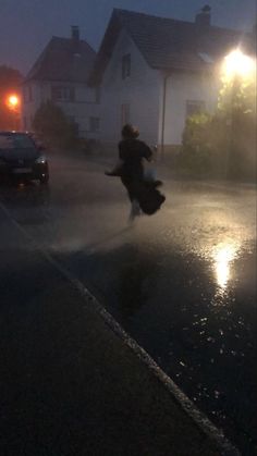 a person jumping in the air on a street at night with cars and buildings behind them