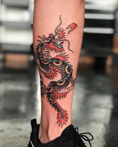 a woman's foot with a dragon tattoo on the side of her leg and black sneakers