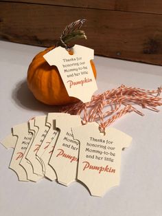 pumpkin tags with thanksgiving sayings on them sitting next to an orange and some twine