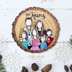 a family portrait on a wooden plaque surrounded by pine cones and snowflakes with the words, the kelims city owl