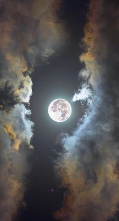 the full moon is seen through some clouds