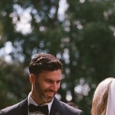 a man in a tuxedo smiles as he walks down the aisle with his bride