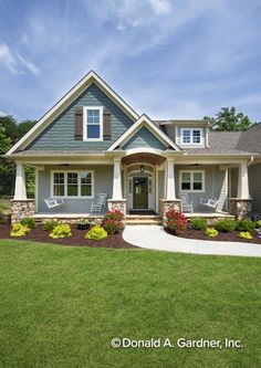 a gray house with white shutters and flowers in the front yard