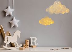 a white shelf topped with toys next to a wall mounted clock and star shaped clouds