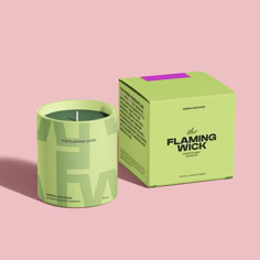 a green candle sitting next to a box on a pink background with the words flaming wick printed on it