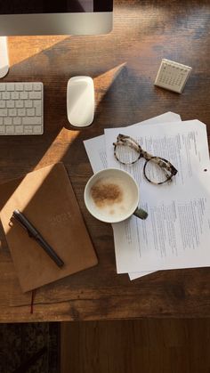 a cup of coffee sitting on top of a wooden desk