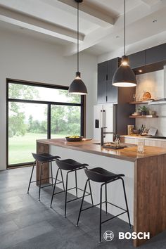 a kitchen with three stools and an island in the middle, along with large windows