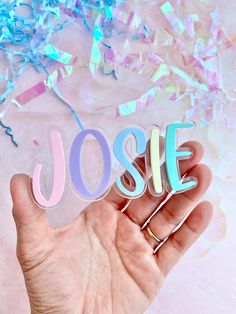 a hand holding the word josie in front of confetti and streamers