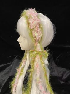 a white mannequin head wearing a green and pink hat with flowers on it