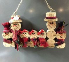 a group of wooden snowmen hanging from a string on a wall in front of a gray background