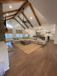 a large open living room with wood flooring and vaulted ceiling, two couches on either side of the fireplace