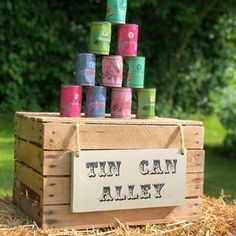 a wooden crate filled with lots of different colored cups sitting on top of hay covered ground