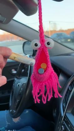 a pink stuffed animal hanging from the dashboard of a car