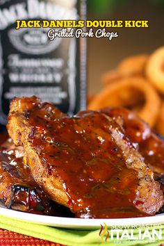 a close up of a plate of food with meat and onion rings in the background