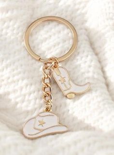 a gold keychain with a cowboy hat and star on the bottom is laying on a white blanket