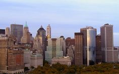 an aerial view of a city with tall buildings and lots of trees in the foreground