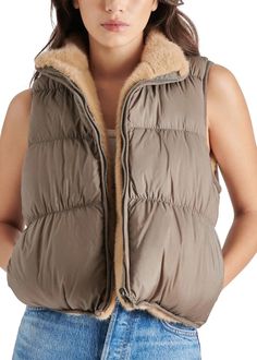 Experience the best of both worlds with this versatile Steve Madden Brady Vest in Grey. One side boasts sleek quilted details for a classic and effortless style, while the other is lined with luxurious faux fur to add a touch of sophistication and comfort. Approx. model height is 5'8" and she is wearing a size small Hits at hip Mock neck; front zip closure Front slant pockets Quilted; reversible with faux-fur side Lined 100% nylon; lining: 100% polyester Hand wash or dry clean If you would like to see photos or speak with a stylist for any further questions please call us at 678-309-9550 during business hours. Puffy Vest, Reversible Vest, Outerwear Vest, Reversible Quilt, Quilted Vest, Camel Color, Puffer Vest, Stand Collar, Effortless Style