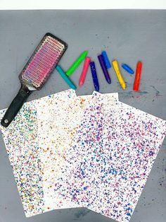 three different colored crayons are on the table next to paper and a spatula