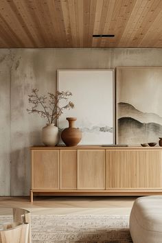 a living room with wooden furniture and paintings on the wall, along with an ottoman