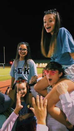 a group of young people standing on top of each other at a baseball field with their hands in the air