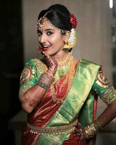 a woman in a green and red sari with her hands on her face, smiling