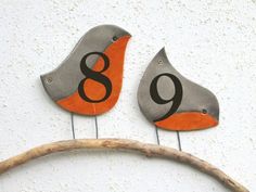 two bird shaped numbers are on the side of a building with a branch in front of them