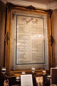 an ornate gold framed menu hangs on the wall next to candles and other items in front of it