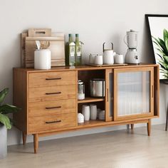 a wooden cabinet with many items on top of it next to a potted plant