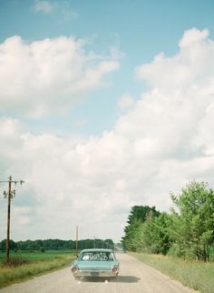 an old car parked on the side of a dirt road