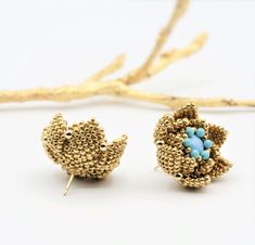 a pair of gold tone earrings with blue beads and leaves on the front, set against a white background