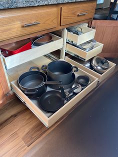 an open drawer with pots and pans in it