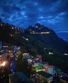 the city lights are lit up at night in the mountainside town below it is illuminated by street lamps