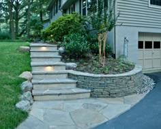 a house with stone steps leading up to the front door and driveway area, along with landscaping