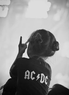 a woman with her hand up in the air while wearing a shirt that says ac dc