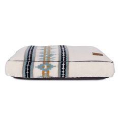 a white and blue dog bed with an embroidered design on the front, sitting against a white background