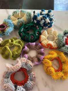 six crocheted hair ties laid out on a marble counter top, all in different colors