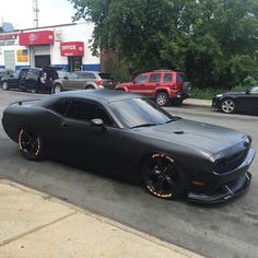 the black car is parked on the side of the road in front of some cars